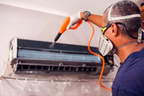Man worker doing professional cleaning of air conditioning. Stock Photos
