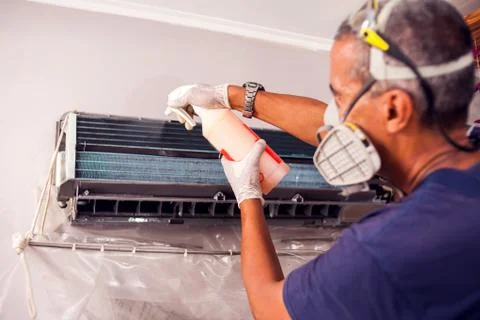 Man worker doing professional cleaning of air conditioning. Stock Photos