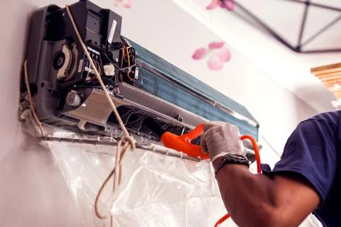 Man worker doing professional cleaning of air conditioning. Stock Photos