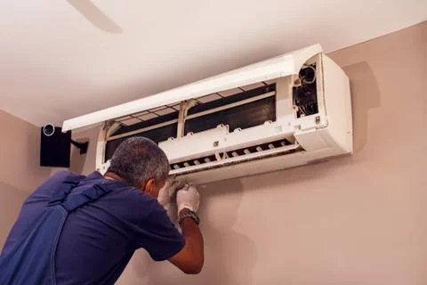 Man worker doing professional cleaning of air conditioning. Stock Photos