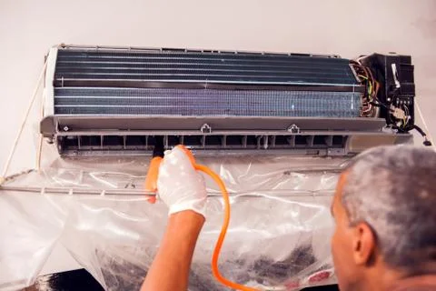 Man worker doing professional cleaning of air conditioning. Stock Photos