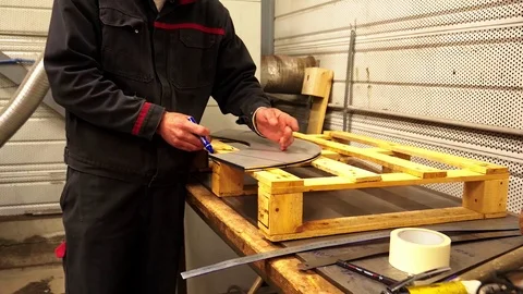 A man worker drawing lines on a stainless steel piece in a factory in slow Vidéo 108458638