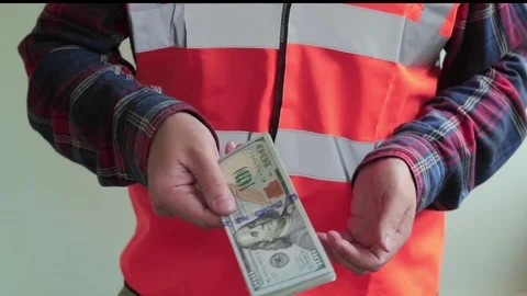 Man worker dressed in a reflective vest count new hundred dollar bills Stock Footage 107220062