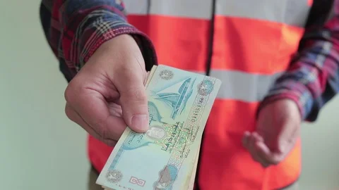 Man worker dressed in a reflective vest count arab bills dirhams Stock Footage 107220090
