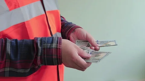 Man worker dressed in a reflective vest count money, new hundred dollar bills Stock-Footage 107220101
