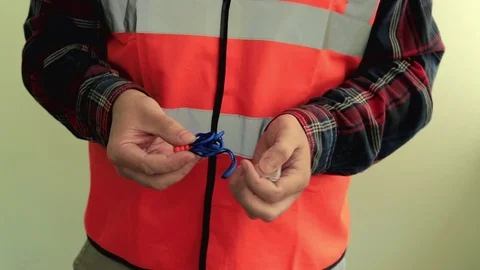 Man worker dressed in a reflective vest holding protective earplugs. Stock Footage 107426089