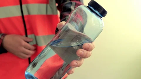 Man worker dressed in a reflective vest give plastic bottle with drinking water 스톡 동영상 107426196
