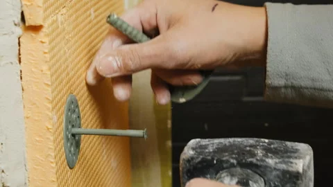 Man worker hammers nail into wall with insulation material Video stock 304411790