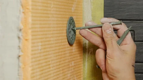 Man worker hammers nail into wall attaching insulation board Video stock 304412502