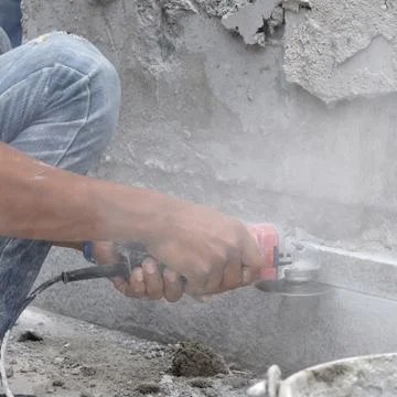 Man worker hands using electric grinder cutting stone. Stock Photos