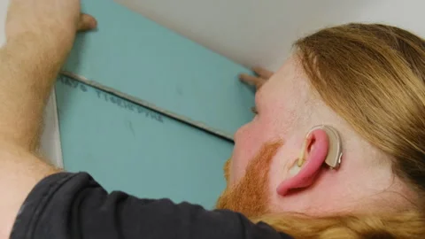 Man worker with hearing aid checks size of gypsum plank to install Stock Footage 304408370