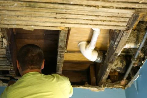 A man, worker looking at broken ceiling. Stock Photos