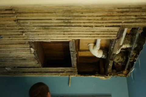 A man, worker looking at broken ceiling. Stock Photos