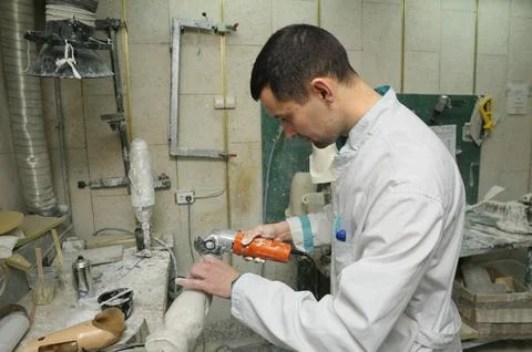 Man worker making artificial limbs using hand cutting machine for further m.. Stock Photos