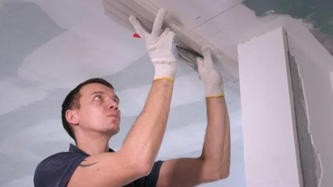 Man worker marks plaster molding with red pencil on ceiling Stock Footage 151784445