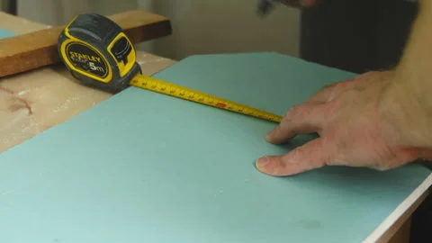 Man worker measures gypsum panel cutting notch with knife Stock-Footage 304408132