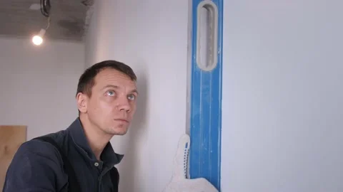 Man worker measures wall evenness with blue waterpass Stock Footage 151784207
