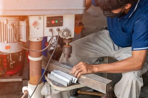 The man worker in metal workshop using pedestal drill Stock Photos