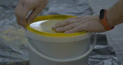 Man worker opens up bucket lid with grey paint for walls Stock Footage 169632064