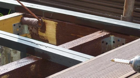 Man worker paint with brown color wooden plank outdoors. Stock Footage 117470528
