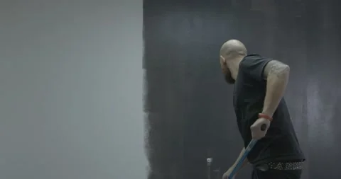 Man worker paints big wall in grey color with roller in room Stock Footage 170148424