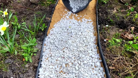 Man worker strewing white decorative split gravel, stones,rocks on path,road,wal Stock Footage 282598331