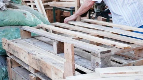 Man Worker in a timber factory using a nail gun to make a wooden pallet Stock Footage 118814295