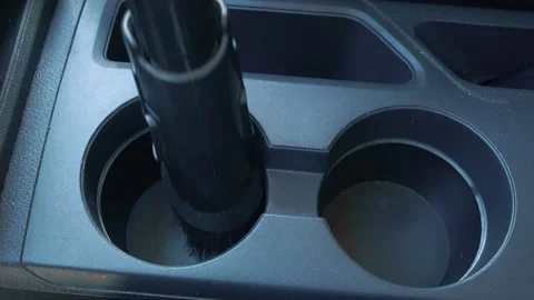 Man worker washes car. Vacuums cup holders in interior of auto Stock Footage 276609157