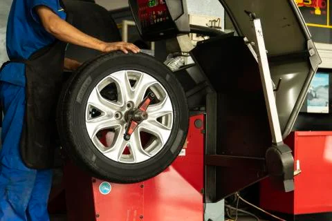Man worker with Wheel balancing machine for car tire repair service. Stock Photos