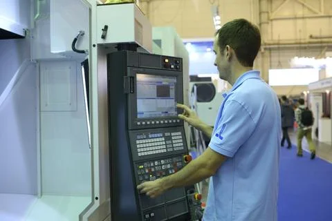Man worker working with a control panel of a CNC milling machine, stand. Stock Photos