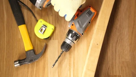 Man with workers glove pressing a cordless drill screw with a plank of wood,  Stock Footage 90769019
