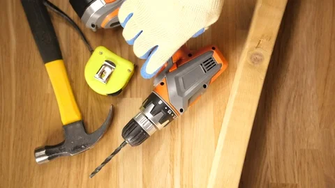 Man with workers glove working a cordless drill with tape measure and hammer  Stock Footage 90767552