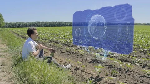 Man is working with 3D Earth on holographic display on the edge of the field Stock Footage 98307594
