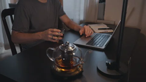 Man working and drinking tea at computer on desktop Stock Footage 295171590