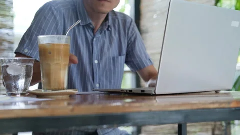 Man working and sipping cold coffee on terrace Stock Footage 312381976