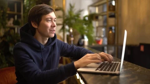 Man working on a aptop in cafe. Young freelancer is sitting in cafeteria on Stock Footage 118964517