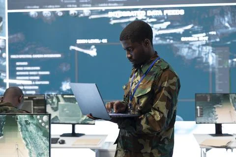 Man working as army analyst using laptop to update mission data Stock Photos