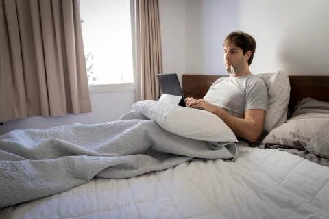 Man working in bed, doing home office because he is sick. Stock Photos