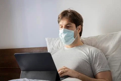 Man working in bed, doing home office because he is sick. Stock Photos
