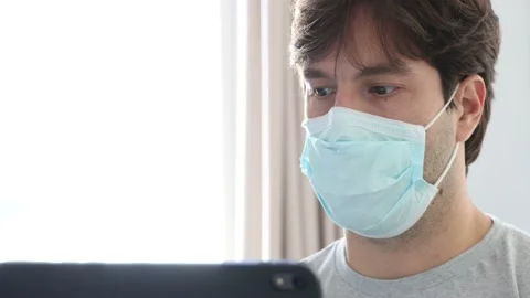 Man working in bed, with a facemark, doing home office because he is sick. in 4k Stock Footage 132360774