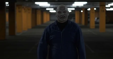 Man in working blue robe and disgusting leather mask stands in front of camera Stock Footage 118875014