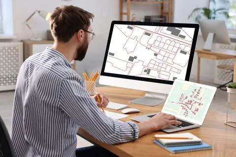 Man working with cadastral map on computers at table in office Foto stock