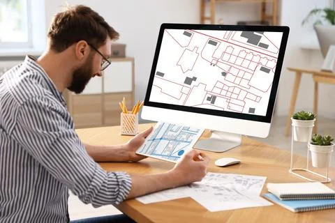 Man working with cadastral map on tablet and computer at table in office Foto stock