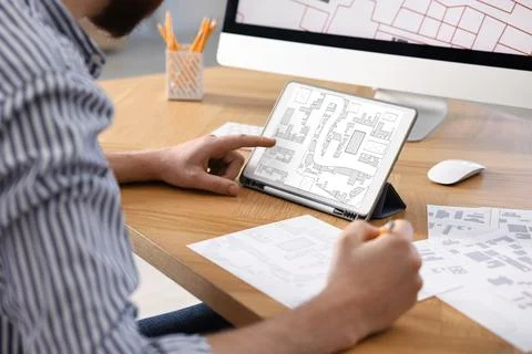 Man working with cadastral map on tablet at table in office, closeup Foto stock
