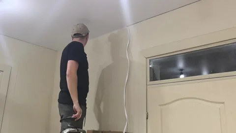 Man working on ceiling while installing trim in a room during evening time Stock Footage 329405481