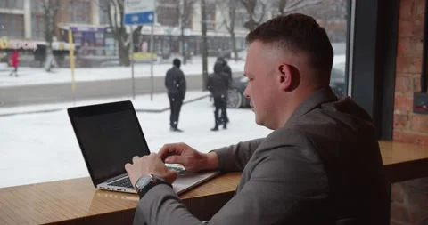 A man is working at a computer and it is snowing outside the window Stock-Footage 167175134