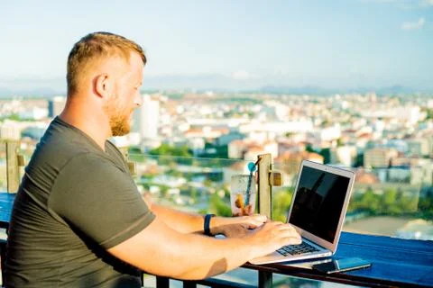 Man working on a computer in a cafe with a beautiful view Stock Photos