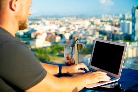 Man working on a computer in a cafe with a beautiful view Stock Photos