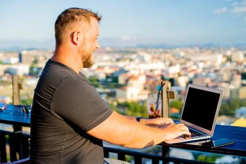 Man working on a computer in a cafe with a beautiful view Stock Photos
