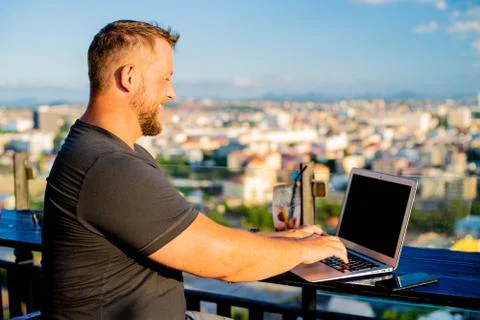 Man working on a computer in a cafe with a beautiful view Stock Photos